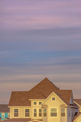 Family house with an off white wall that contrasts with the brown roof