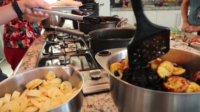 Side view of a pan. Cooking some bananas in the pot. Women making Mole in Puebla Mexico. North America. Two people grinding some ingredients. Cooking Traditional recipe.