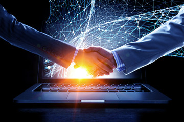 Business handshake by a man and a woman, and a laptop. Mixed media.