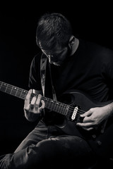 one man, playing guitar, dark and moody rock musician. Black and white image.