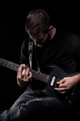 one man, playing guitar, dark and moody rock musician. Black and white image.