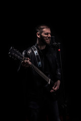 musician playing guitar and singing on a microphone