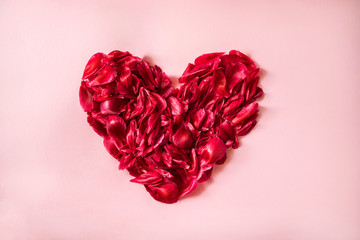 Obraz na płótnie Canvas Heart shape made from peony petals on pink background.