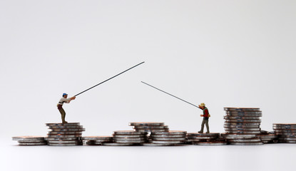 Miniature people fishing on coin piles.