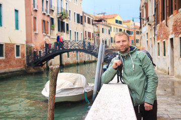 Fototapeta na wymiar Young guy in Venice, Italy. Man posing on narrow venetian canal of Venezia