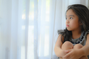 Depressed Little girl near window at home, closeup