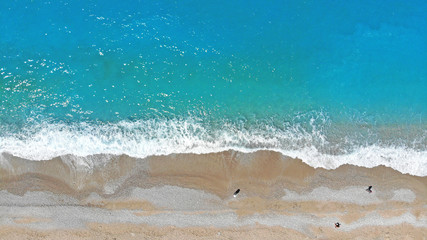 Aerial. Beautiful blue sea water and waves on a beach. Top view. Holiday background.