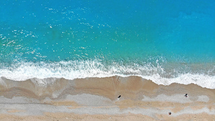 Aerial. Beautiful blue sea water and waves on a beach. Top view. Holiday background.