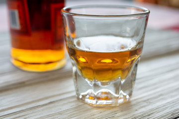 A whiskey bottle and shot glass on a rustic wooden surface