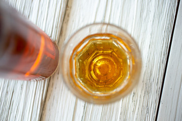 A whiskey bottle and shot glass on a rustic wooden surface