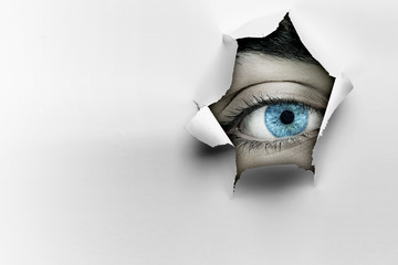 Eye in a hole of torn paper