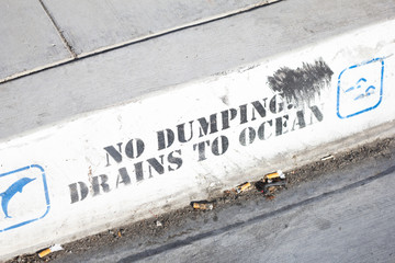 A rain drainage area with a sign that says No Dumping Drains to ocean
