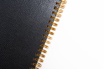 An elegant spiral-bound notebook or journal with elegant textured faux leather hard cover artfully set and composed on a plain white background.