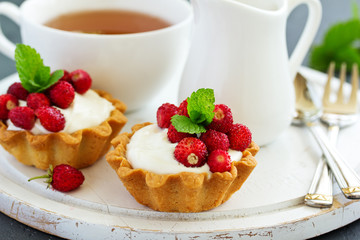 Wild strawberry tartlets with cream filling. delicious summer fruit mini tarts