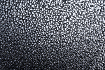 A macro or close-up shot of the visible and raised textured grain of a faux black leather with dramatic side lighting.