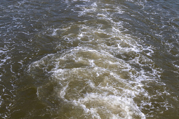 Top view on the water surface behind a fast driving ship