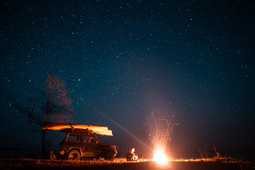 Happy man sitting in front burning bonfire