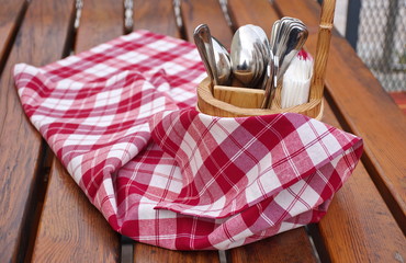 Rustic tablecloth and wooden container with eating utensil on the wooden table