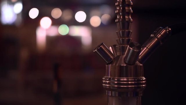 Toxic hookah sheesha vaporizing smoking instrument in a lounge, close up shot