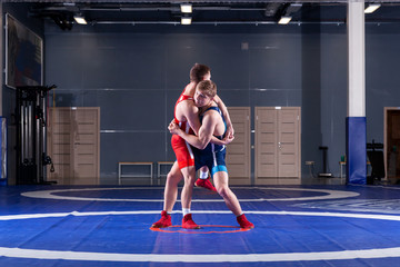 The concept of fair wrestling. Two greco-roman  wrestlers in red and blue uniform wrestling   on a wrestling carpet in the gym