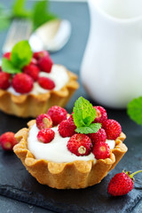 Wild strawberry tartlets with cream filling. delicious summer fruit mini tarts