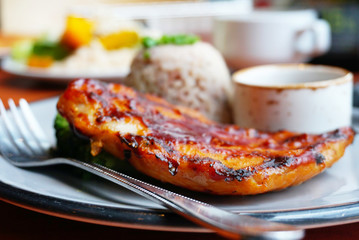 Closeup grill chichen steak with riceberry and source on the dish.
