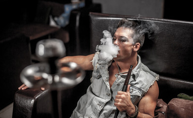 Man is blowing smoke in night club.