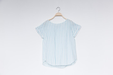 A female blue stripe blouse with wooden hanger isolated white background.