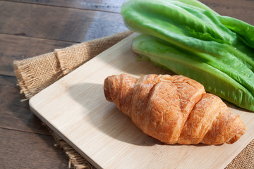 Croissant and salad vegetable on wooden table. Healthy food. Breakfast concept