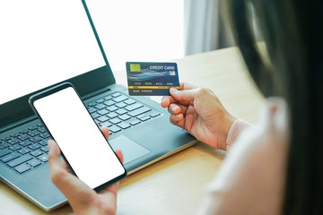 Asian young woman hands holding credit card and using laptop smartphone for online shopping concept