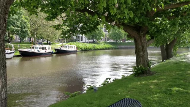 Old Church Tower Oldehove Leeuwarden fast dolly shot in front the river EE with moored boats in the park