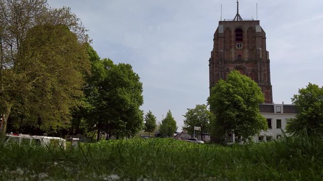 Old Church Tower Oldehove Leeuwarden fast dolly shot in front the river EE with moored boats in the park