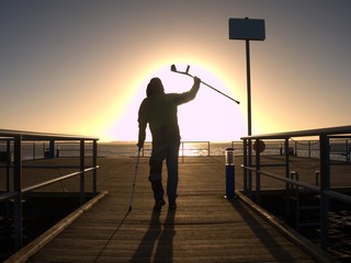 Fototapeta premium Hard walk of hurt man with crutches on port pier.