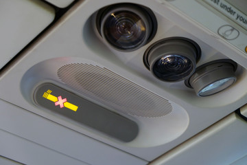 No smoking sign on the overhead information panel in the airplane above the passenger seat