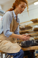 Focused young lady enjoying time spending in pottery workshop