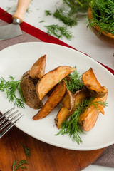 Baked potato wedges with dill. Cafe menu on a wooden background in warm colors with copy space.