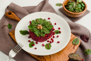 Beet salad with pomegranate, walnuts, prunes and spinach. Cafe menu on a wooden background in warm colors with copy space.