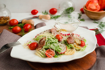 Salad with roasted meat, radish, lettuce, cherry tomatoes, cheese, and pickled cucumbers. Cafe menu on a wooden background in warm colors.