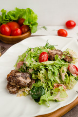 Salad with beef, lettuce, cherry tomatoes, and mayonnaise dressing. Cafe menu on a wooden background in warm colors with copy space.