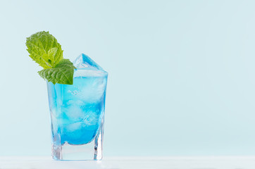 Tropical fresh blue shot drink with curacao, ice cubes, green mint in exquisite misted shot glass...