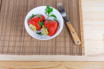 Cooked stuffed red bell peppers in white bowl and fork