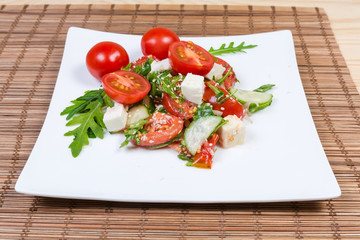Salad of fresh cherry tomatoes, mozzarella, greens on dish