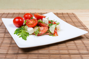 Salad of fresh cherry tomatoes, mozzarella, greens on dish