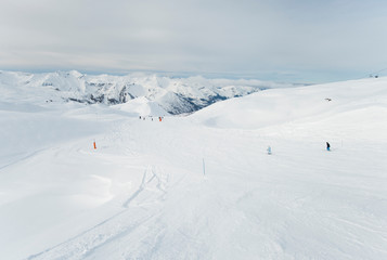 Fototapeta na wymiar Skiers on a piste in alpine ski resort