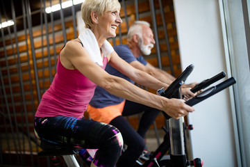Happy senior people doing indoor biking in a fitness club