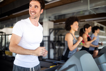 Happy fit people running on treadmill at fitness gym club