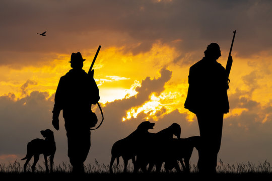 hunters with dogs at sunset