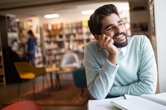 Smiling male student working and learning in a library