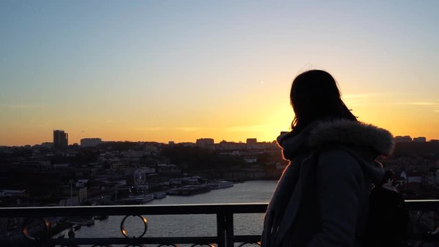 young woman walking and enjoying an european historic city at sunset by herself. Cold sunny weather and wearing a winter coat. Portugal is a perfect travel destination for young tourists. 