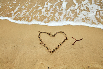 Heart shaped symbol on a sandy beach in summertime.